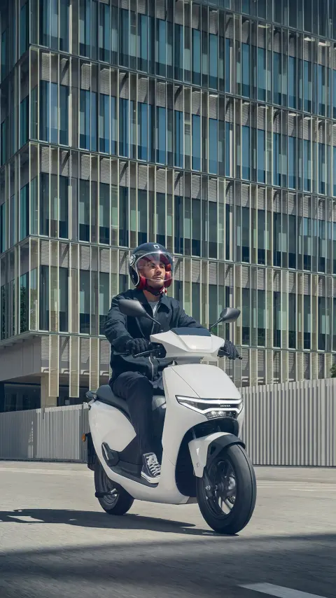 Fotómodell a Honda CUV e motorkerékpár nyergében egy utcai helyszínen.