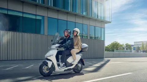 Fotómodellek a Honda CUV e: motorkerékpár nyergében egy városi helyszínen.