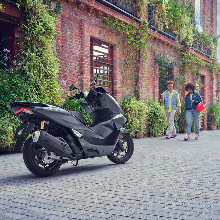 Fotómodellek sétálnak a PCX125 motorkerékpár irányába.