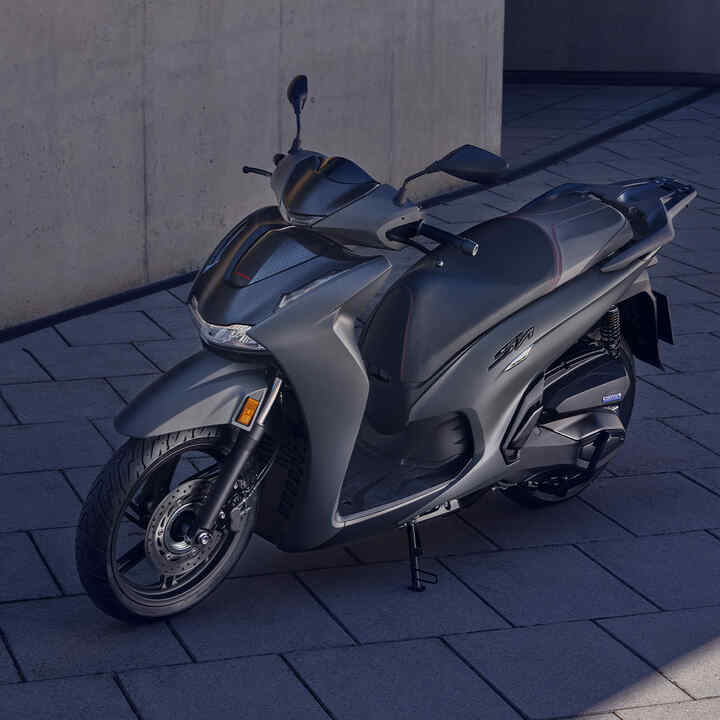 Elölről készült háromnegyedes felvétel egy álló Honda SH350i modellről egy udvaron.