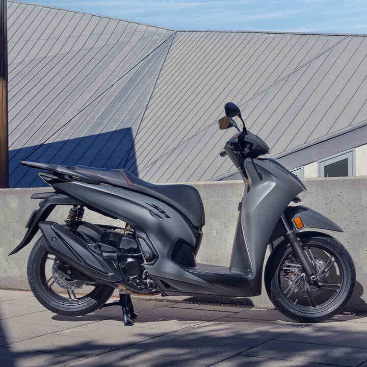Oldalról készült felvétel az álló Honda SH350i modellről egy udvaron