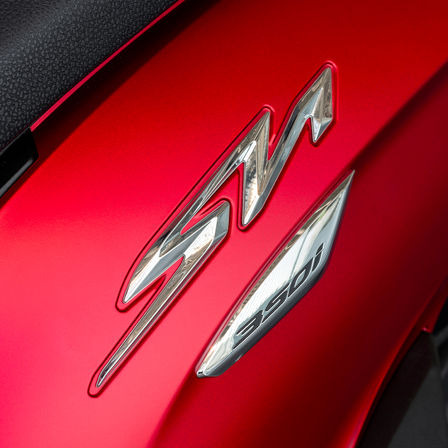 Honda SH350i, közelkép az SH emblémáról, piros motorkerékpár