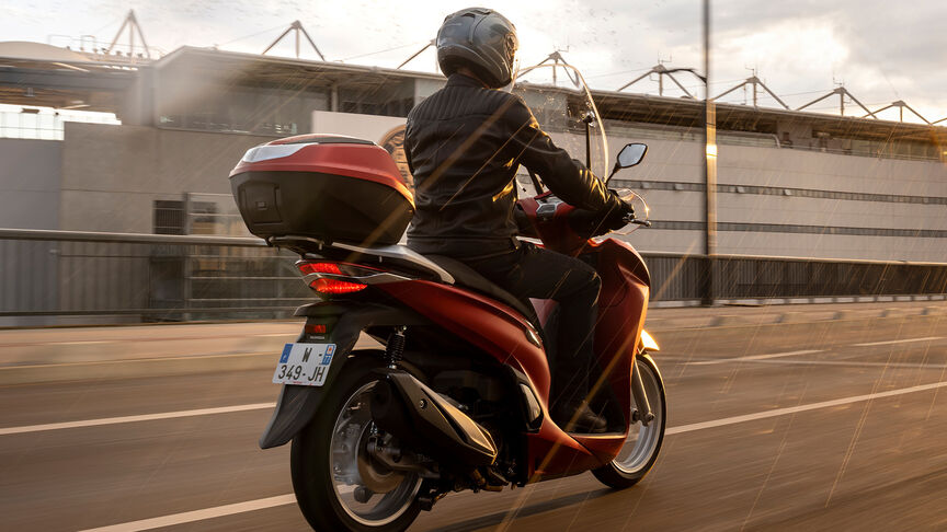 Honda SH350i, háromnegyedes, jobb elölről készült felvétel, motorossal, közúton, piros motorkerékpár