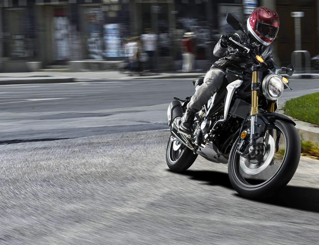 Háromnegyedes felvétel egy utcán haladó Honda CB300R Neo Sports Café-ról.