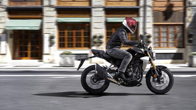 Oldalról készített akciókép egy közúton haladó Honda CB300R Neo Sports Café-ről.