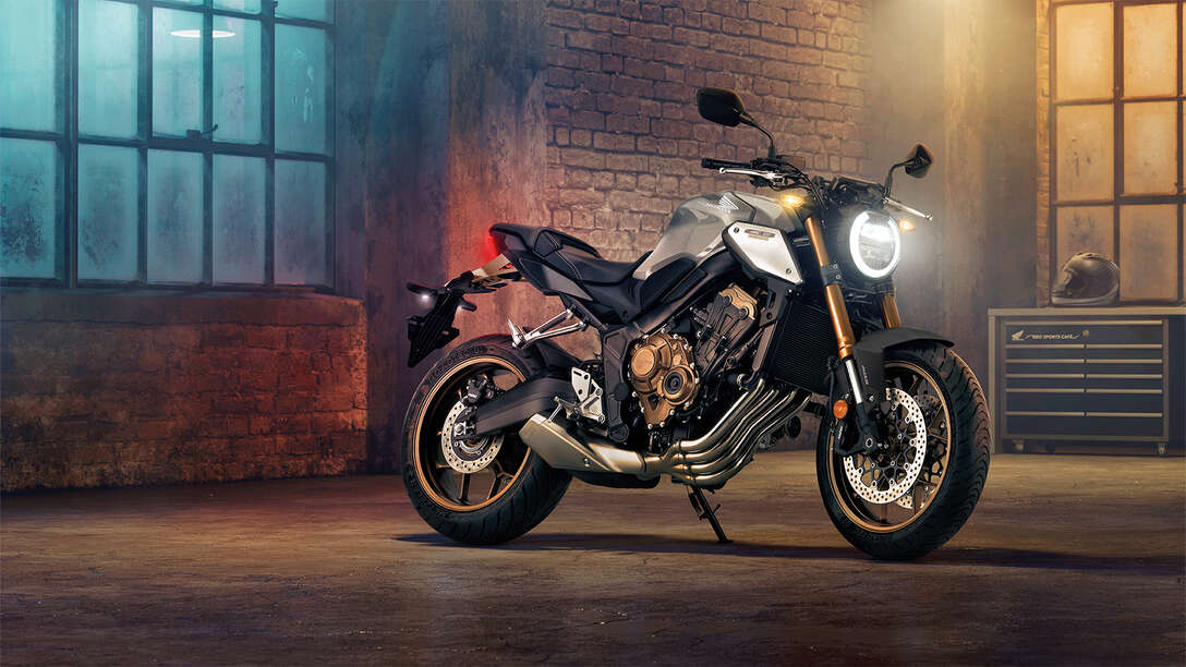 Háromnegyedes, elölről készült felvétel a CB650R Neo Sports Café jobb oldaláról városi környezetben éjszaka