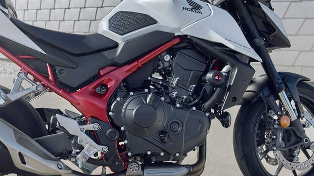 Honda CB750 Hornet és egy férfi, aki egy épületnek támaszkodik.