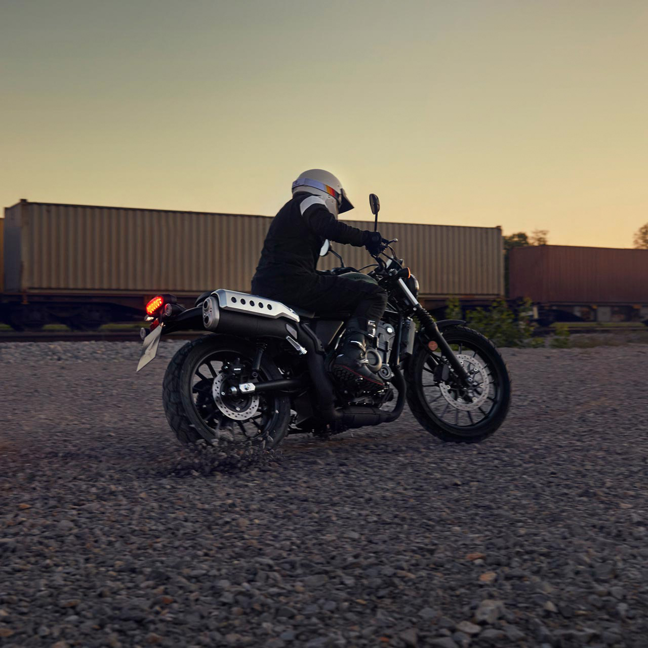 Egy modell egy Honda CL500 motorkerékpárt vezet egy raktárhelyszínen.