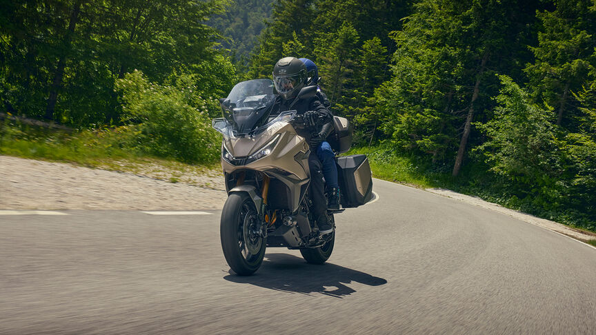 Az NT1100 oldalnézetből, motorossal, városi környezetben