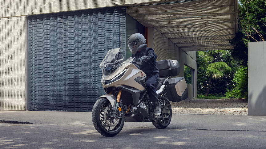 Az NT1100 oldalnézetből, motorossal, városi környezetben