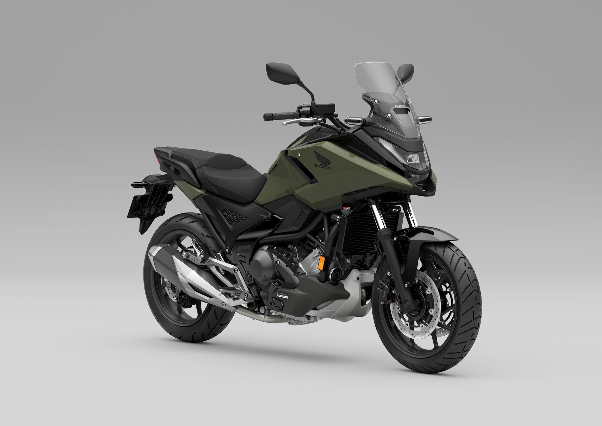 A Honda NC750X motorcycle in matte green color, featuring a windscreen, upright riding position, and adventure-touring styling, shown against a plain gray background.